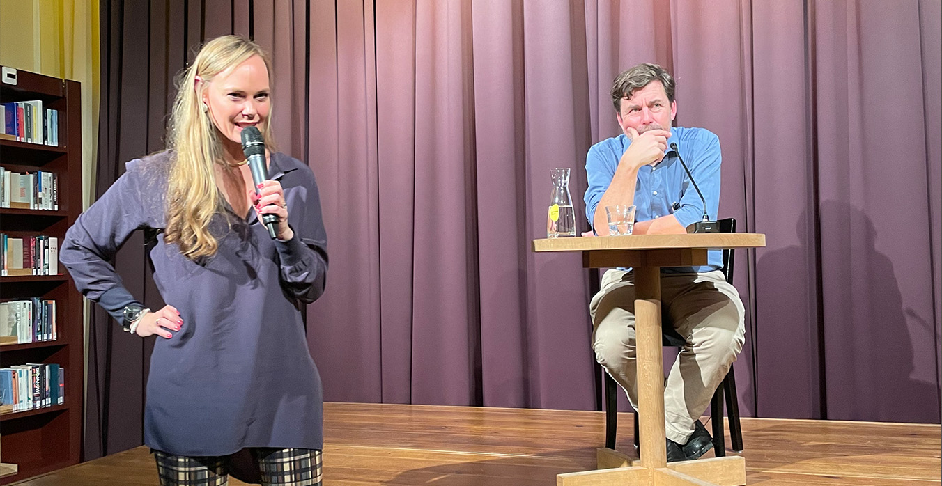 Das Bild zeigt Milo Rau an einem kleinen Tisch sitzend, auf der Bühne im Literaturhaus Zürich.