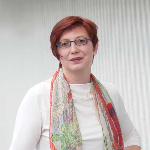 Das Bild zeigt Sabine Schneider mit kurzem rotem Haar und Brille. 