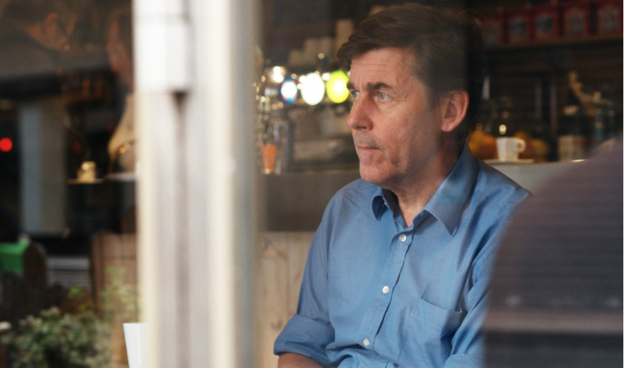 Das Foto zeigt den nachdenklich blickenden Peter Stamm, er sitzt in einem blauen Hemd in einer Bar.