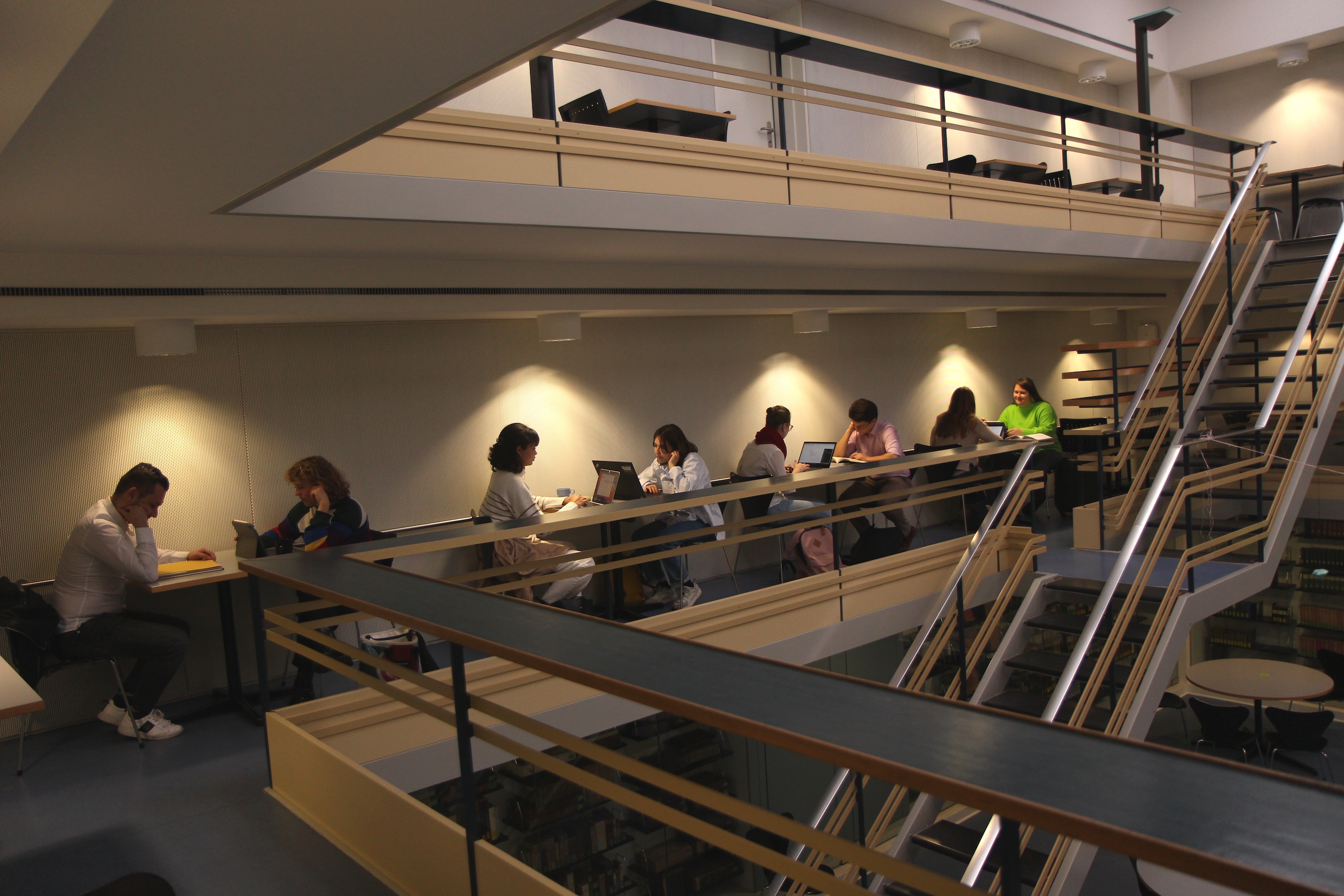Das Bild zeigt den Lernraum am Deutschen Seminar, Studierende sitzen an kleinen, hell beleuchteten Tischen und lernen.